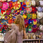 Women standing in front of colorful woven baskets and bags on a market stall in the souk in Aswan, Egypt