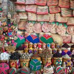 "Colorful woven baskets and bags fill the space around piles of spices and herbs in a market stall in the souk in Aswan, Egypt"