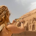 Female in vacation taking pictures with her smart phone the incredible Abu Simbel Temple rebuilt on the mountain in southern Egypt in Nubia next to Lake Nasser Egypt, Aswan, Abu Simbel