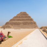 The Step Pyramid, Sakkara, Egypt - July 26, 2022: Saqqara, also spelled Sakkara or Saccara in English is an Egyptian village in Giza Governorate, that contains ancient burial grounds of Egyptian royalty, serving as the necropolis for the ancient Egyptian capital, Memphis.
Saqqara contains numerous pyramids, including the Step Pyramid of Djoser, sometimes referred to as the Step Tomb, and a number of mastaba tombs. Located some 30 km (19 mi) south of modern-day Cairo, Saqqara covers an area of around 7 by 1.5 km (4.3 by 0.9 mi).
Saqqara contains the oldest complete stone building complex known in history, the Step Pyramid of Djoser, built during the Third Dynasty. Another sixteen Egyptian kings built pyramids at Saqqara, which are now in various states of preservation. High officials added private funeral monuments to this necropolis during the entire Pharaonic period. It remained an important complex for non-royal burials and cult ceremonies for more than 3,000 years, well into Ptolemaic and Roman times.