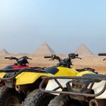 Colorful parked quad bikes ATV safari in desert with pyramids in background Cairo, Egypt. No people